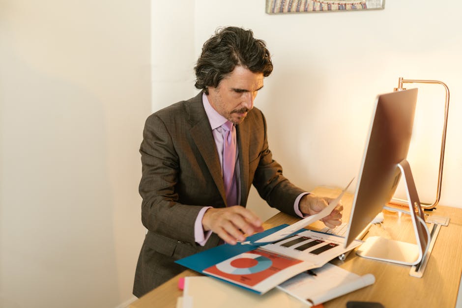 Businessman in suit reviewing financial documents in modern office space.